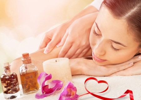 woman getting massage with flower, candle, and oils